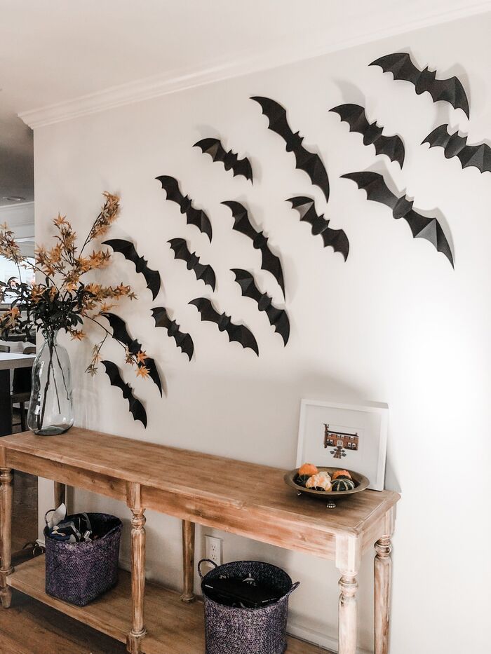 paper bats on a white wall halloween decor in a living space with wooden furniture