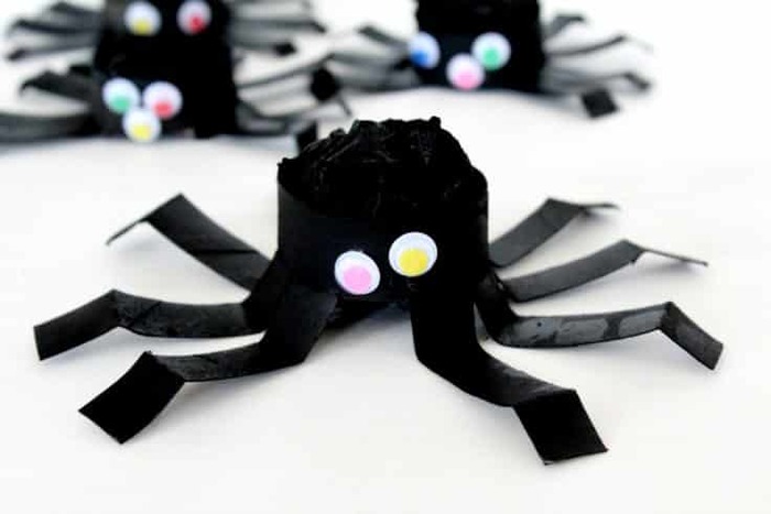 bouncy black spiders on a white table top with colorful eyes