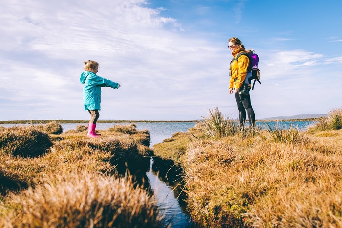 daughter and mom enjoying some time outdoors in a field with water around 