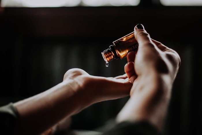 woman in a dark room dropping essential oil in her palm