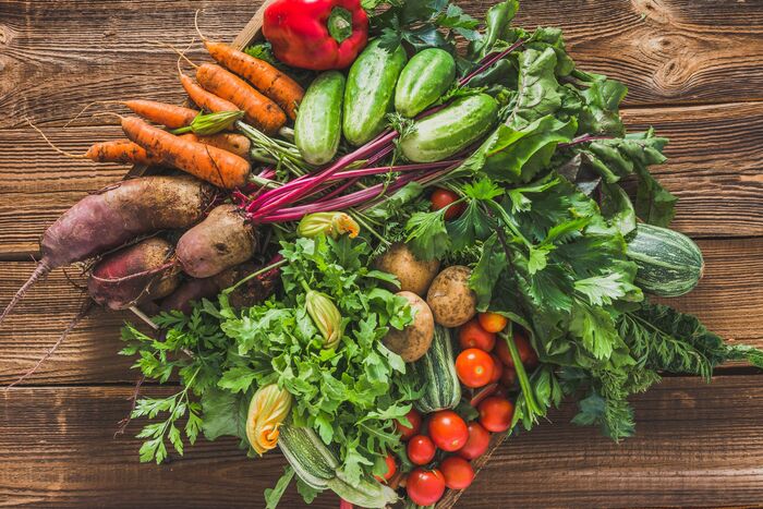 large basket of different fall vegetables on a wooden table