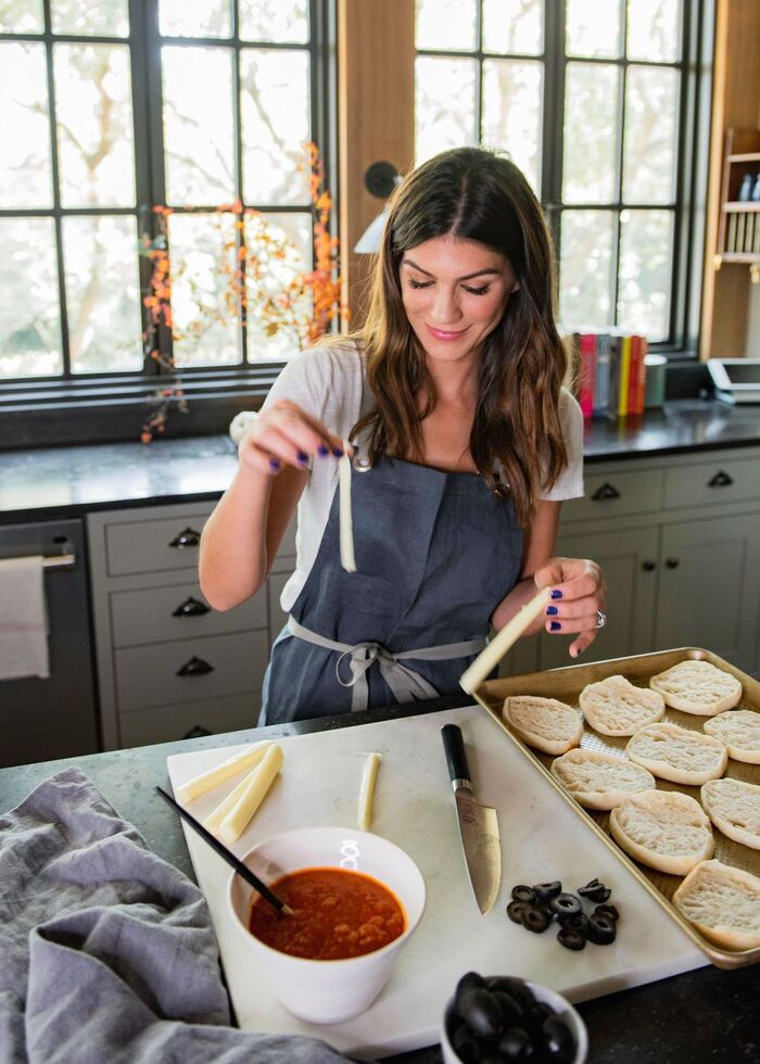 halloween cooking woman in the kitchen with a dark long hair preparing spooky halloween food in a dark apron with two large windows in the back