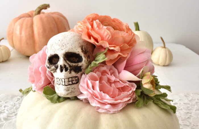 halloween pumpkins on a table in pastel colors white pumpkin with a skull and faux flowers