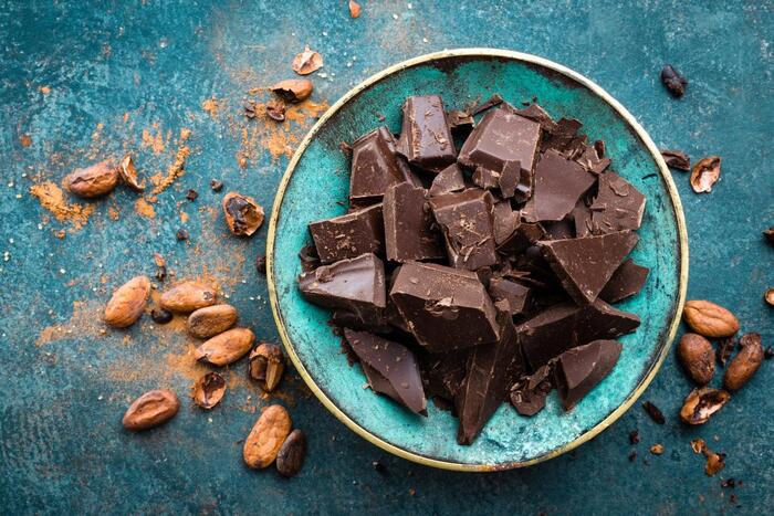 healthy chocolates on a blue table in a blue bowl with cocoa nibs around