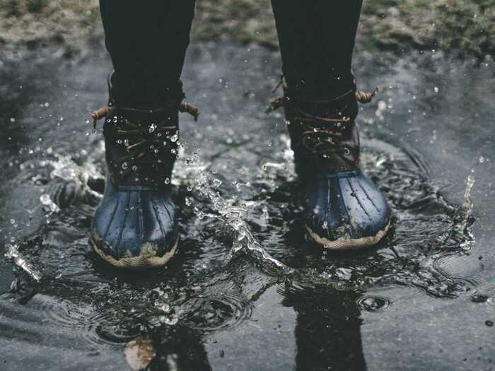 child in black shoes in the rain outdoors on the street