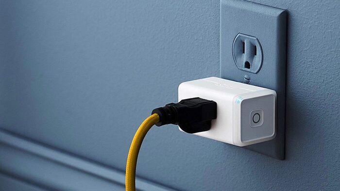 kasa smart wi fi plug in yellow cable and a grey wall with a white socket