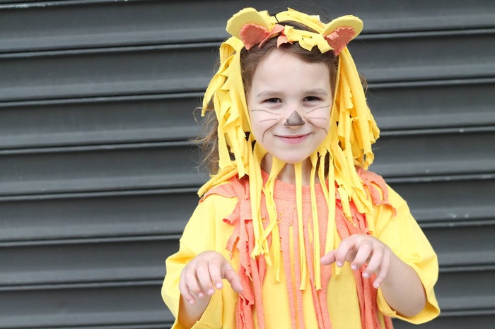 little boy in front of a black garage door in a no sew yellow and orange lion costume