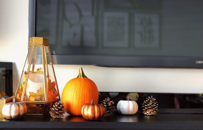 modern home decor small pumpkins pinecones and a golden lantern in front of a large flat tv