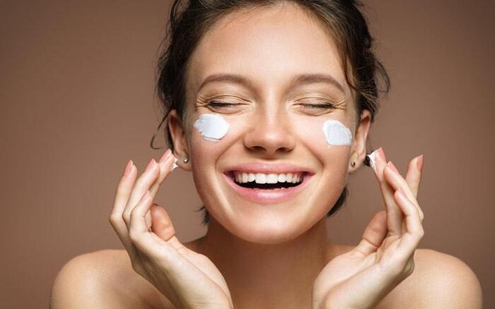 moisturizer woman smiling in the camera with moisturizing cream on her cheeks