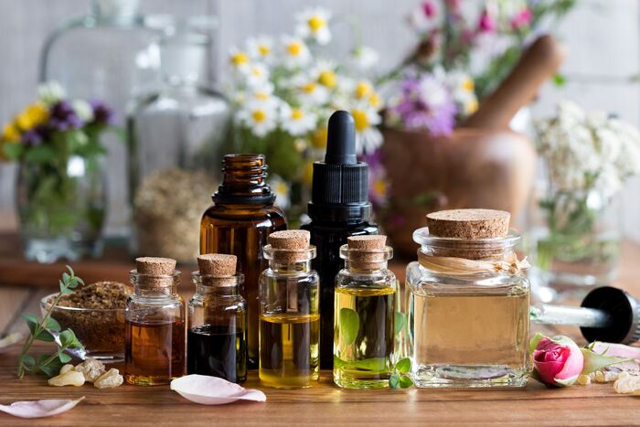oils for cold days essential oil collection with glass containers in different sizes and herbs in the background