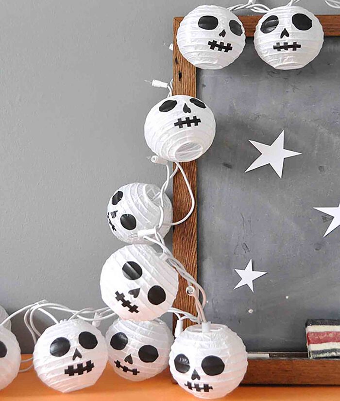 spooky halloween paper lanterns with skull faces on them surrounding a wooden frame