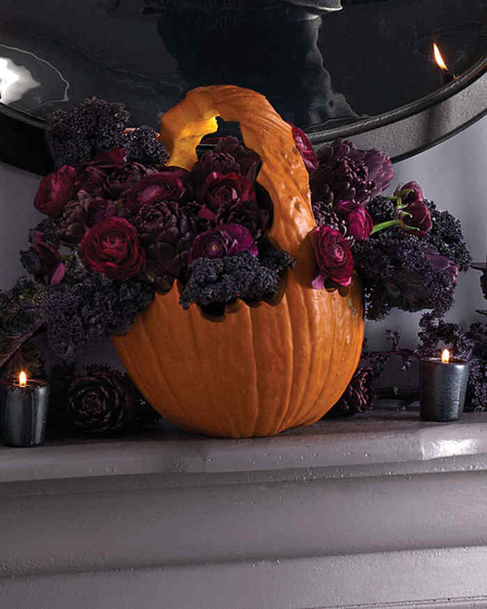 carved pumpkin basket on a mantel with a spooky halloween flower arrangement of dark flowers 