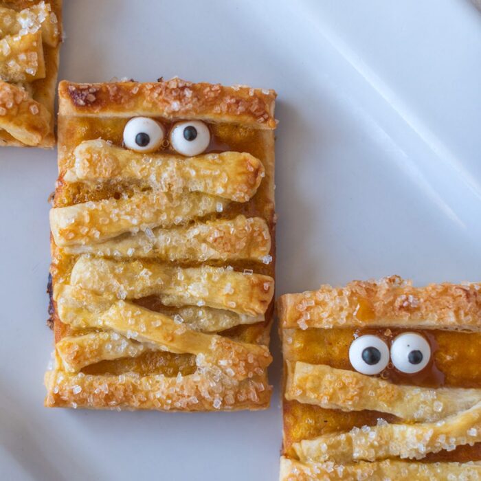 pumpkin mummy cookies close up on a white plate with funny googly eyes