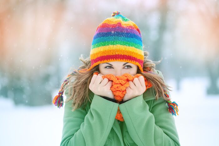 stay warm in winter woman outside with a colorful hat and a thick orange knitted scarf in a green top