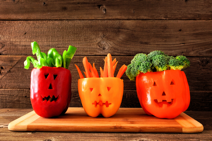 fresh halloween veggies different peppers on a wooden cutting board wooden wall in the background