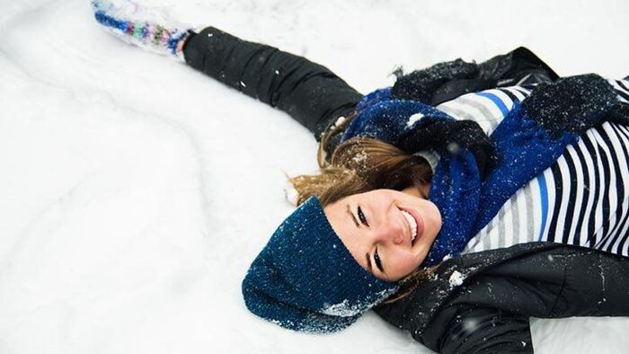winter season change woman dresses in black and blue lying in the snow