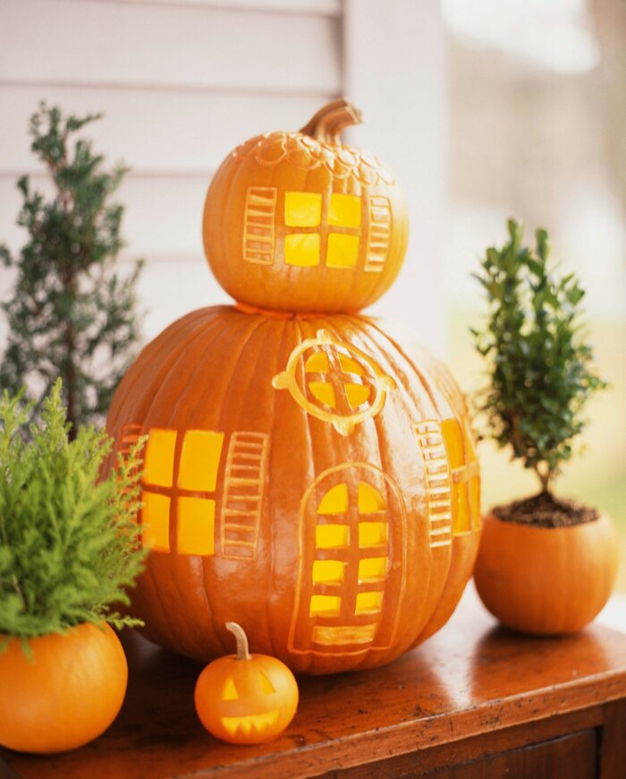 two carved pumpkins stacked on top of each other in an indoor setting fall decor