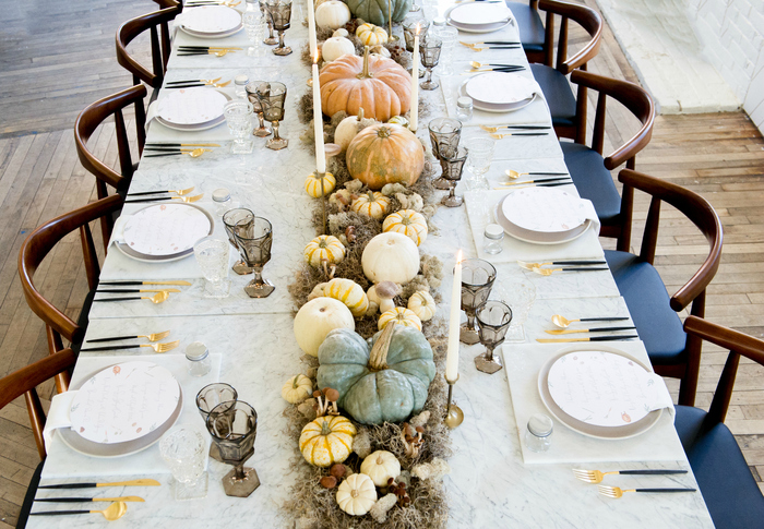 dining table design with different colors pumpkins and tall candles and golden utencils