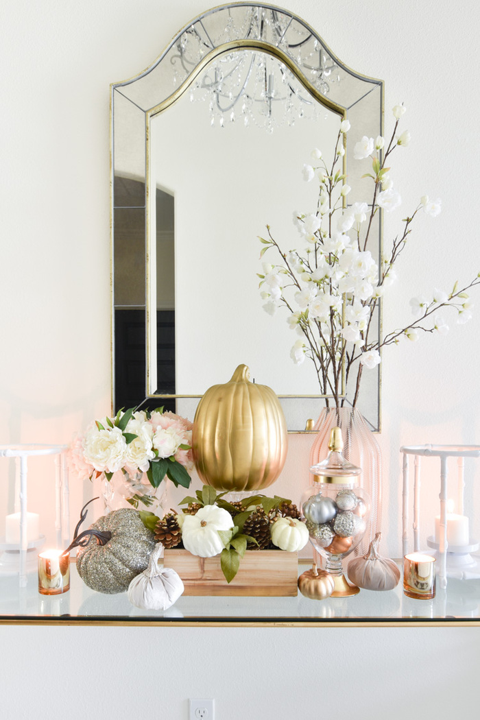 modern pumpkin home decor golden and silver pumpkins in front of a mirror on a glass table with lanterns