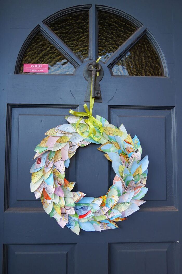 colorful wreath made of map cut outs hanging on a blue door