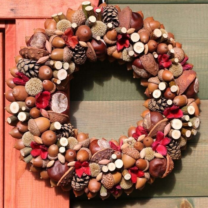 fall wreath made of acorns chestnuts pinecones and other nuts and branches hanging on the door