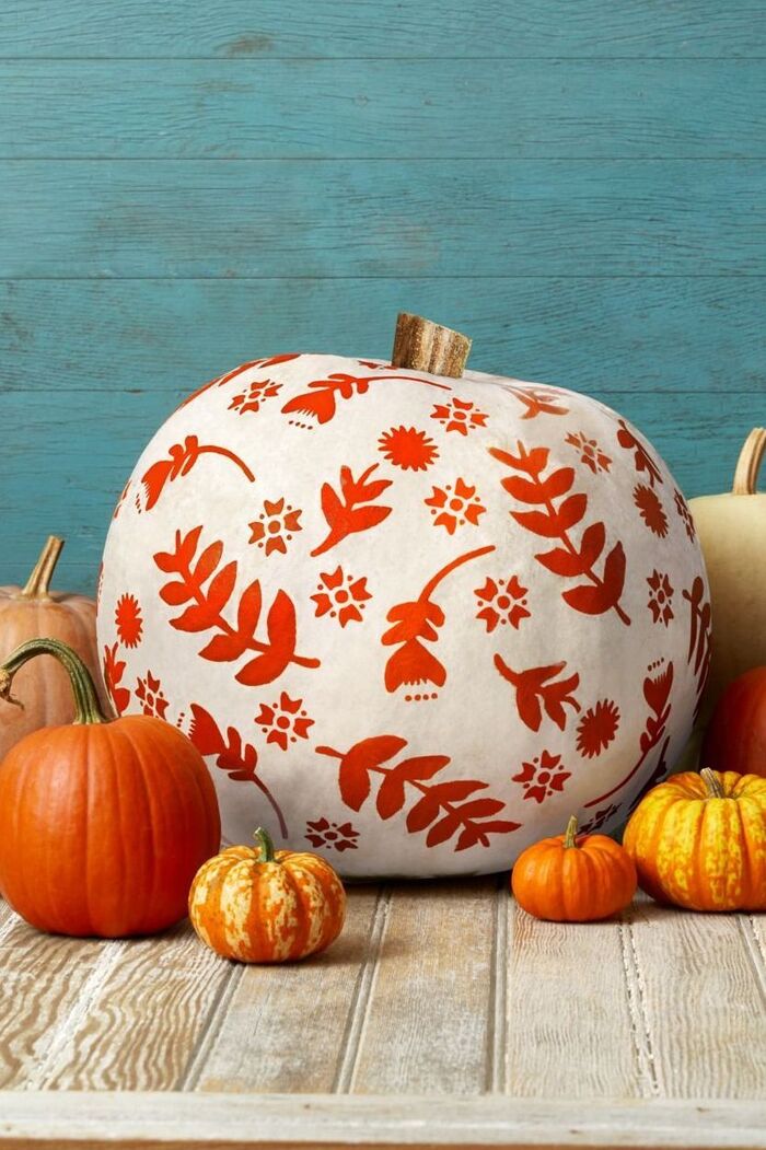 painted pumpkins large white one and smaller orange pumpkins on a wooden table surface