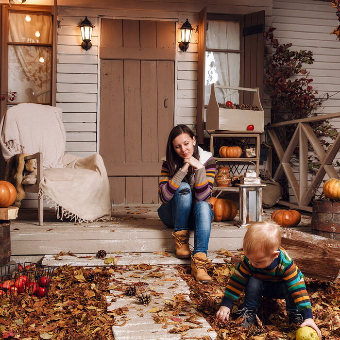 porch fall decor ideas mother and son sitting on a decorated porch with autumn leaves and pumpkins