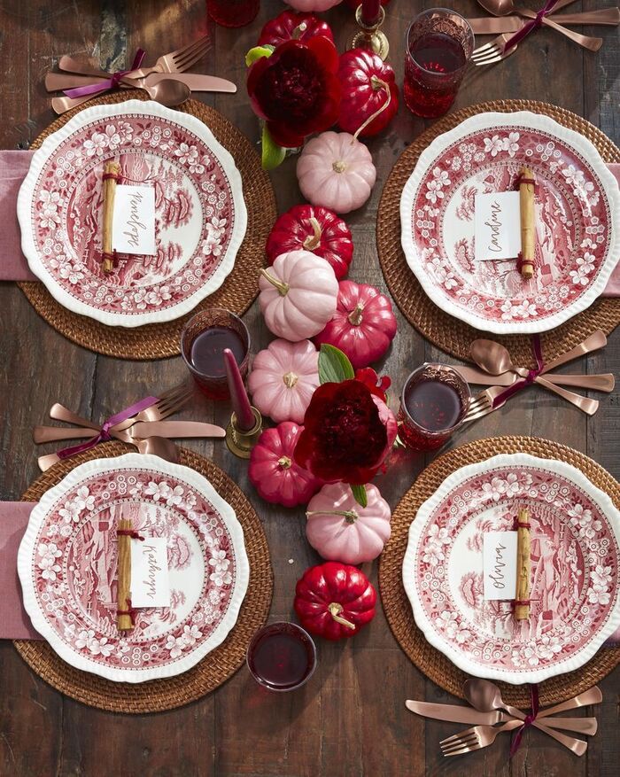 red table setting with retro plates pink and red little pumpkins on a dark wooden table