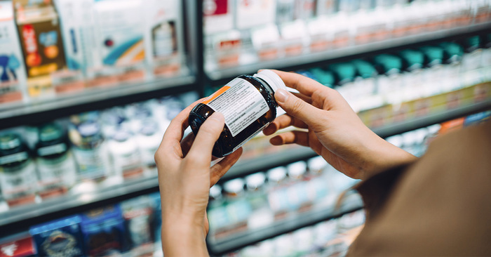 woman holding in her hands a bottle of supplements in a pharmacy