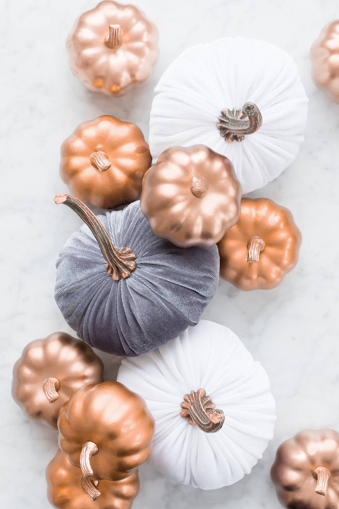 golden and textile pumpkins scattered on a white surface 