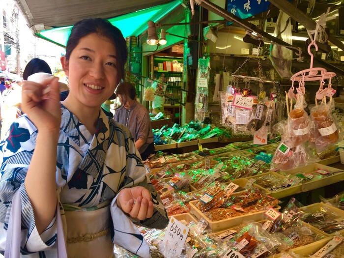 Tsukiji Fish Market Asian woman in kimono at the market tasting food and looking at the camera