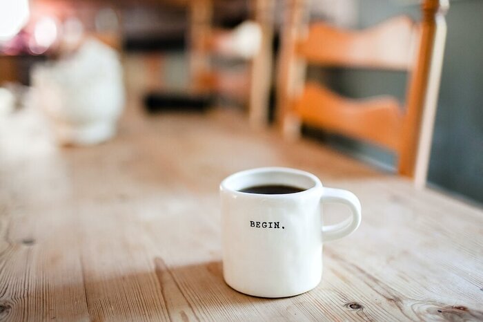white coffee cup on a wooden table with the word Begin on it 