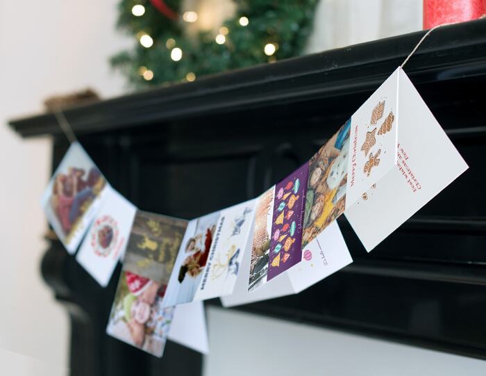 christmas card garland hanging on a black mantel