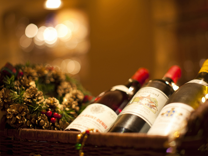 choosing wine for the holidays three bottles of wine in a basket with a holiday wreath next 