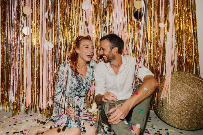 couple laughing and sitting on the floor with sparkling decorations around them