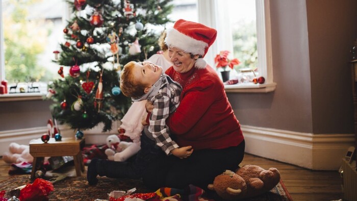 granny and grandchild laughing and having fun in front of a christmas tree