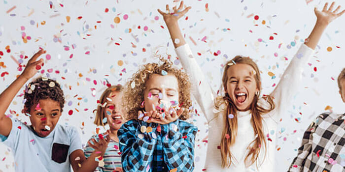 children laughing and spreading colorful confetti on a white background