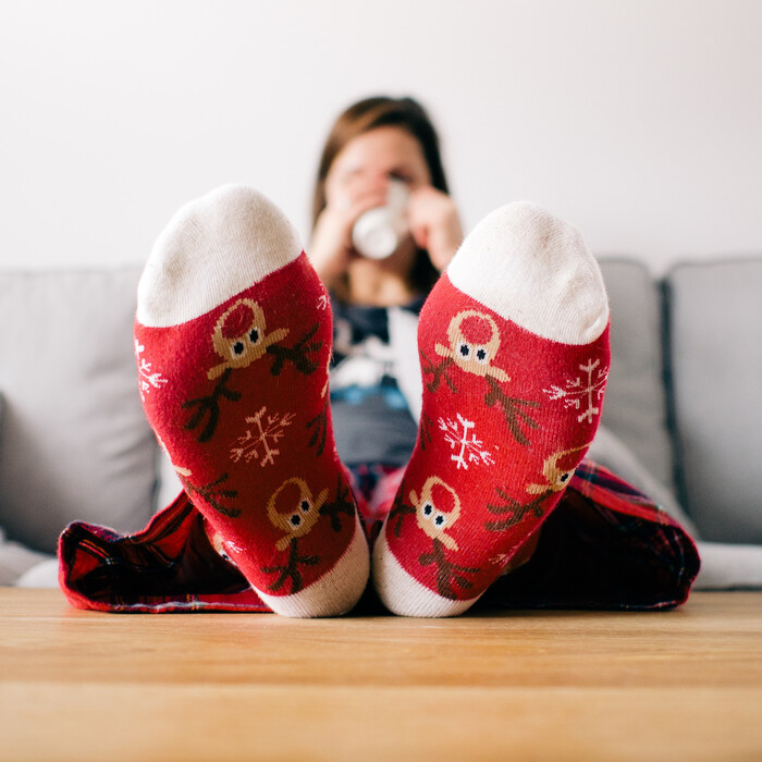 woman relaxing on a couch with her feet in funny red christmas stockings on the table in front