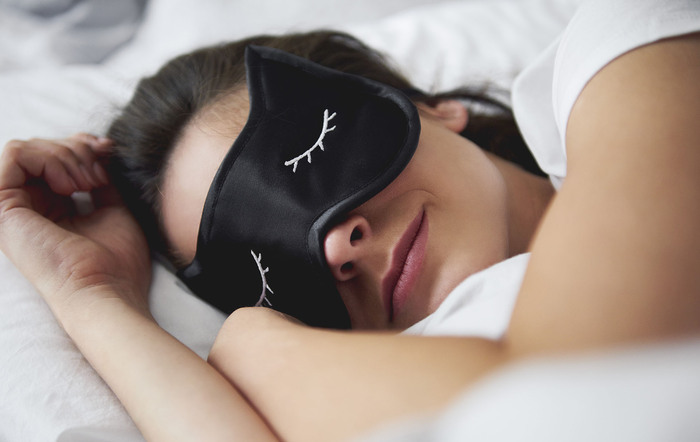 Portrait of young woman with sleep mask in bed