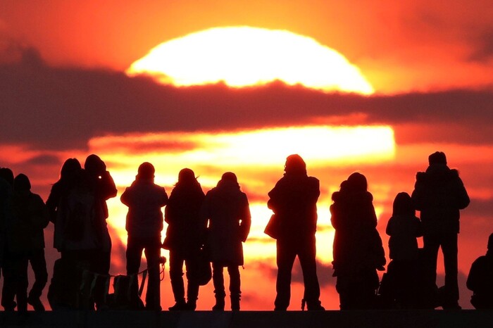 group of people standing on a high spot watching the sunrise 