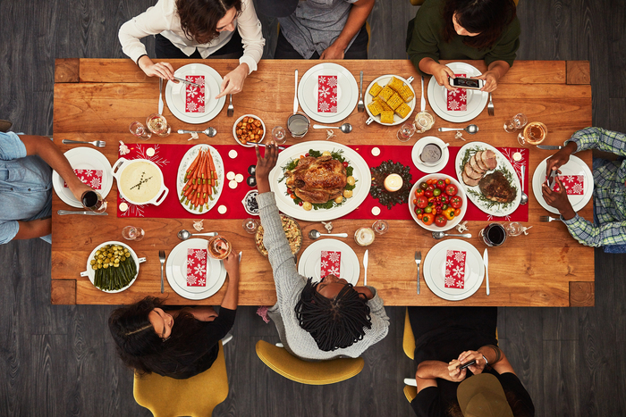 family gathering around a rich table with different dishes people eating and talking