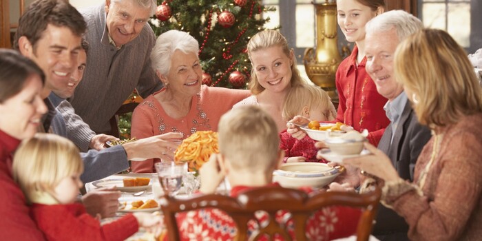 family holiday gathering around the christmas table laughing and tasting the meals