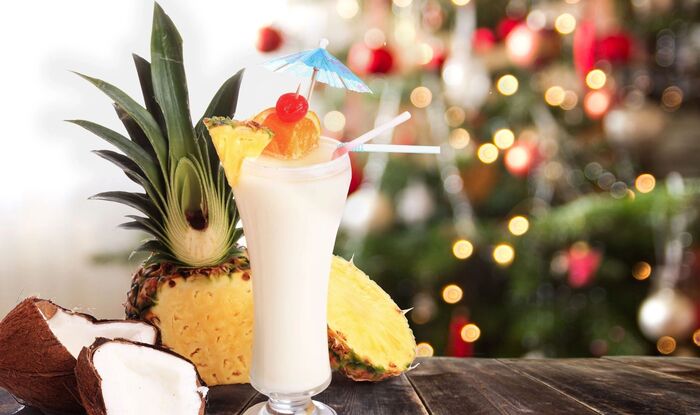 tropical christmas pna colada cocktail with coconut and pineapple in front of a christmas tree
