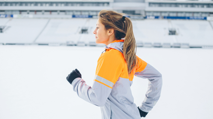 winter routines woman in her sportswear running outdoors in a snow covered stadium