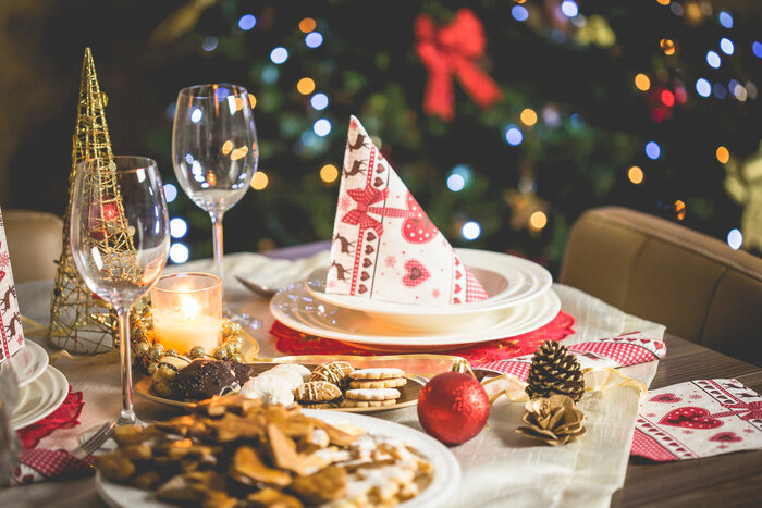 Christmas table with cookies tall wine glasses cute decorations and a tree at the background