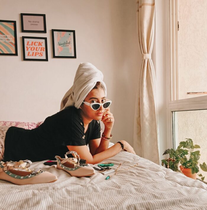 Post-holiday detox woman lying on a bed with her sunglasses on and a towel on her hair