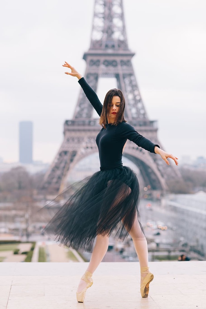 woman dressed like a black ballerina dancing in front of the Eiffel tower