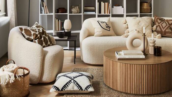 japandi style living room space with soft couch and a light wooden table library in the background