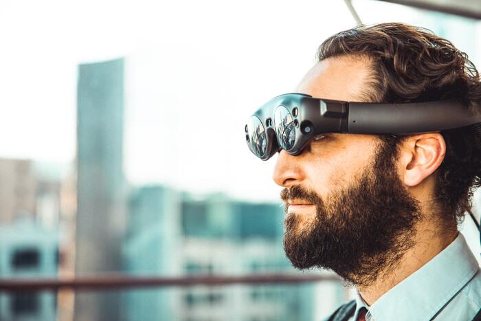 man wearing a modern virtual reality glasses looking out on a city skape