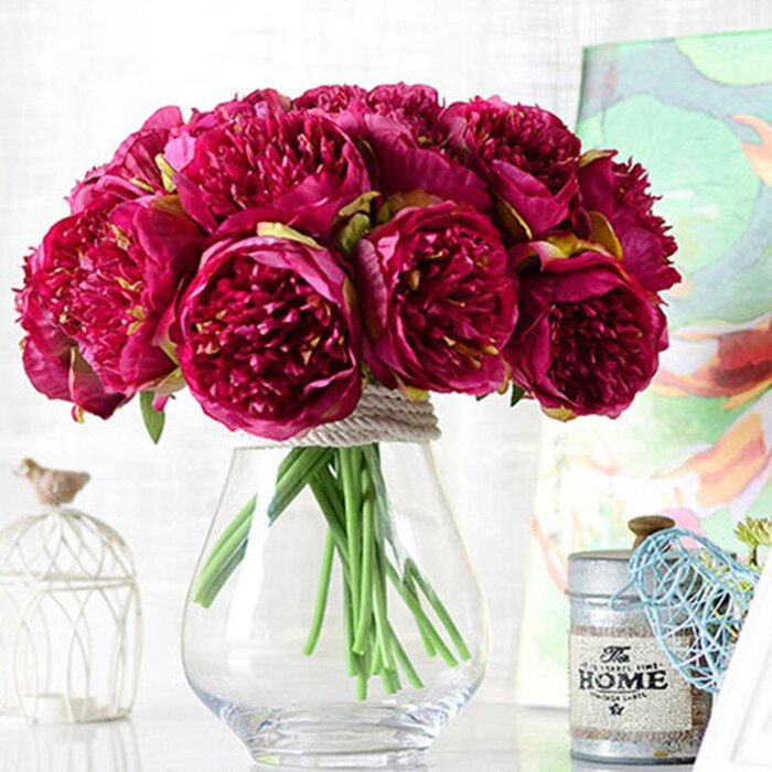 fresh flower bouquet of red peonies in a glass vase in a home office environment